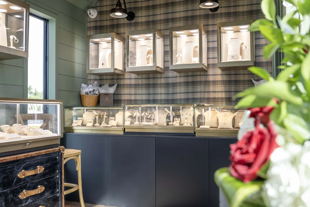 Interior photo of "The Jeweled Barn," an upscale jewelry store housed in a mobile "tiny home," showing glass jewelry display cases on counters,
